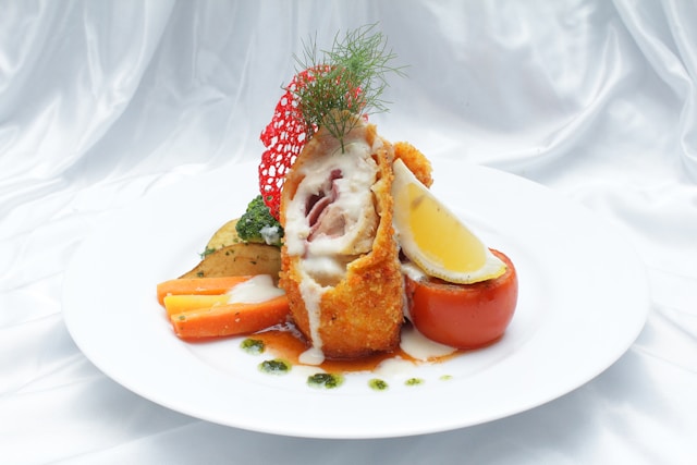 A photo with a serving of a stuffed, fried chicken cutlet with vegetables