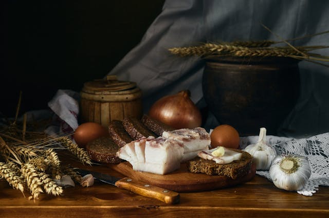 A photo of a wooden board with rye bread and cured lard