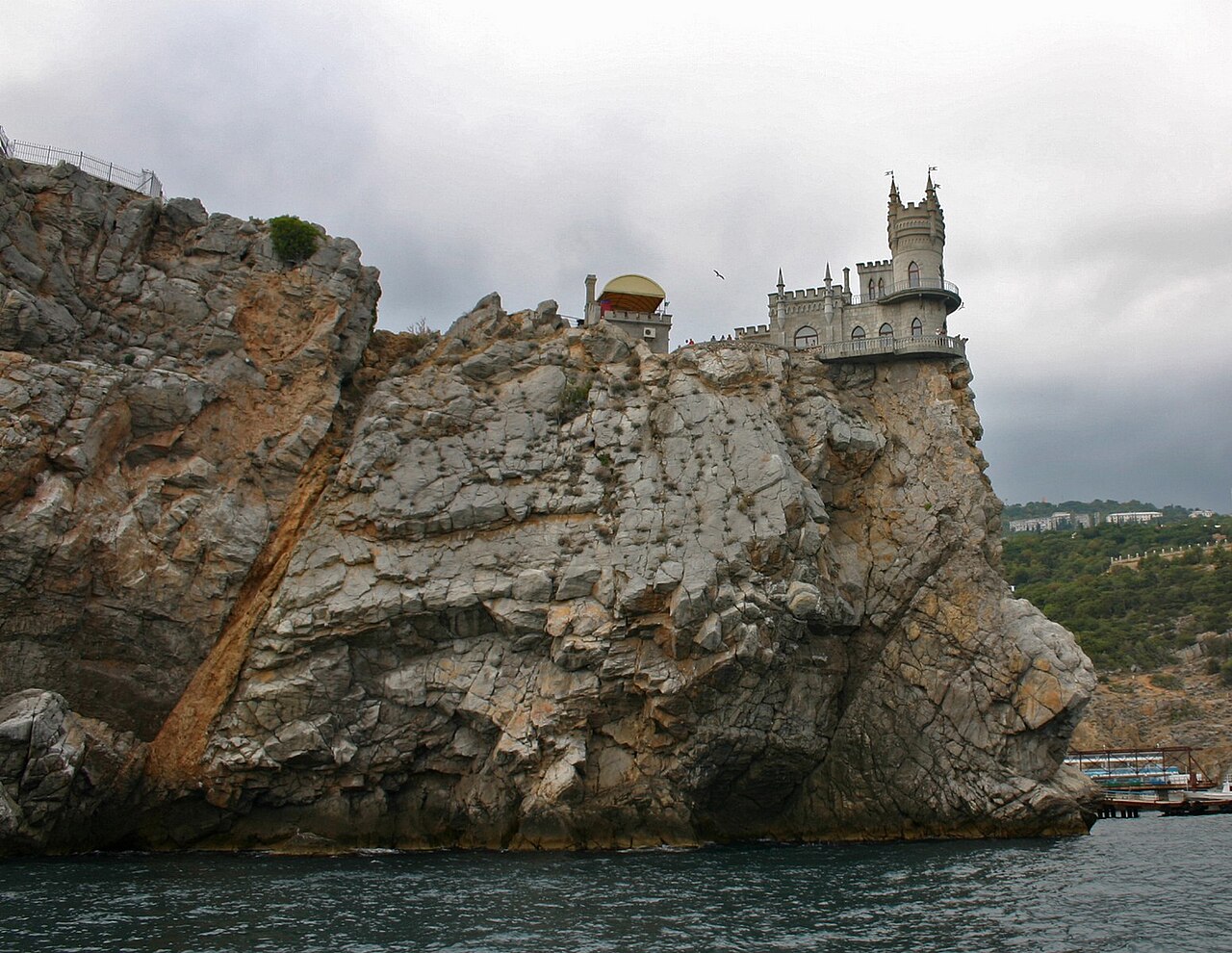 A photo depicting a small castle on the edge of a cliff