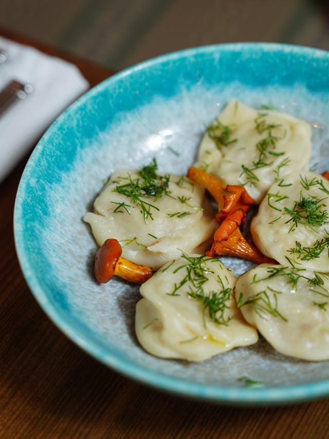 A photo of 2 plates with dumplings with sauce